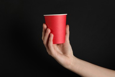 Photo of Woman holding paper cup on black background, closeup. Mockup for design