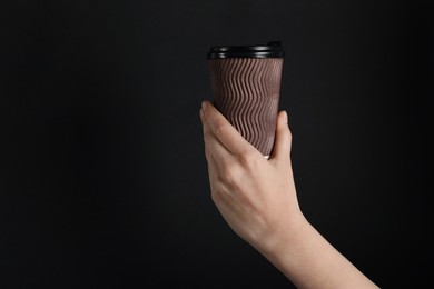 Photo of Woman holding paper cup on black background, closeup. Mockup for design