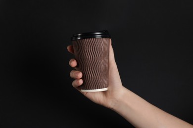 Photo of Woman holding paper cup on black background, closeup. Mockup for design