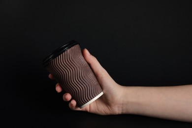 Photo of Woman holding paper cup on black background, closeup. Mockup for design