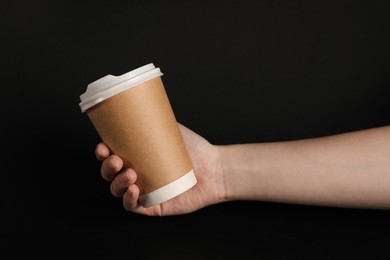 Photo of Woman holding paper cup on black background, closeup. Mockup for design