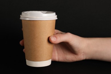 Photo of Woman holding paper cup on black background, closeup. Mockup for design
