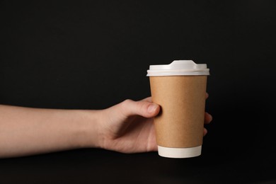 Photo of Woman holding paper cup on black background, closeup. Mockup for design