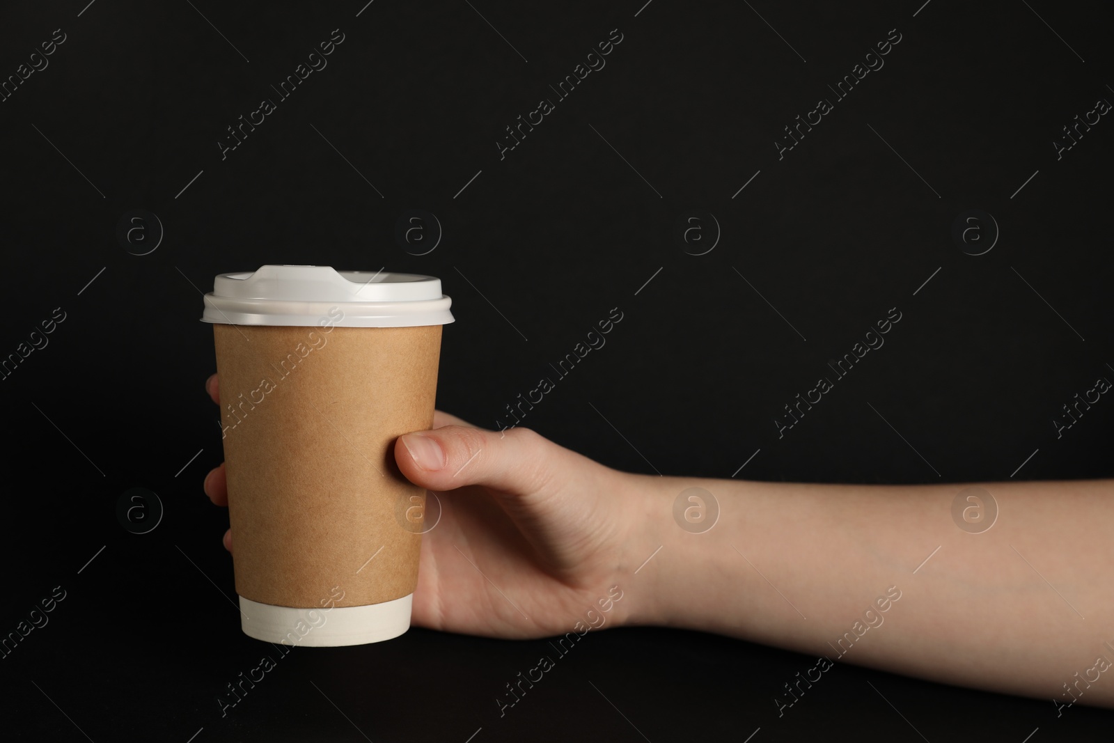 Woman holding paper cup on black background, closeup. Mockup for design Photo of Woman holding paper cup on black background, closeup. Mockup for design