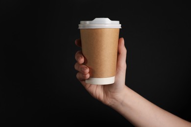 Photo of Woman holding paper cup on black background, closeup. Mockup for design