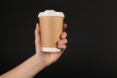 Photo of Woman holding paper cup on black background, closeup. Mockup for design