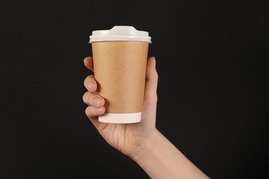 Photo of Woman holding paper cup on black background, closeup. Mockup for design