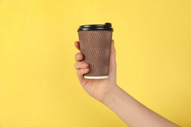 Photo of Woman holding paper cup on yellow background, closeup. Mockup for design