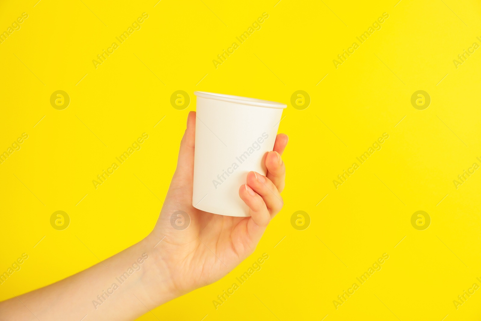 Woman holding paper cup on yellow background, closeup. Mockup for design Photo of Woman holding paper cup on yellow background, closeup. Mockup for design