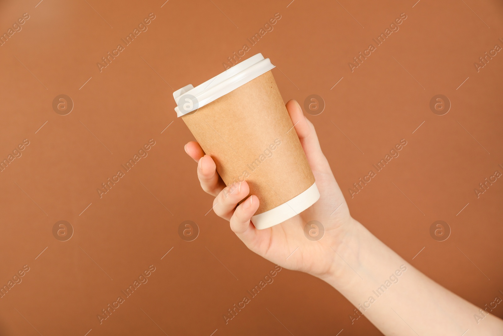 Woman holding paper cup on brown background, closeup. Mockup for design Photo of Woman holding paper cup on brown background, closeup. Mockup for design
