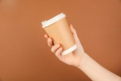 Photo of Woman holding paper cup on brown background, closeup. Mockup for design
