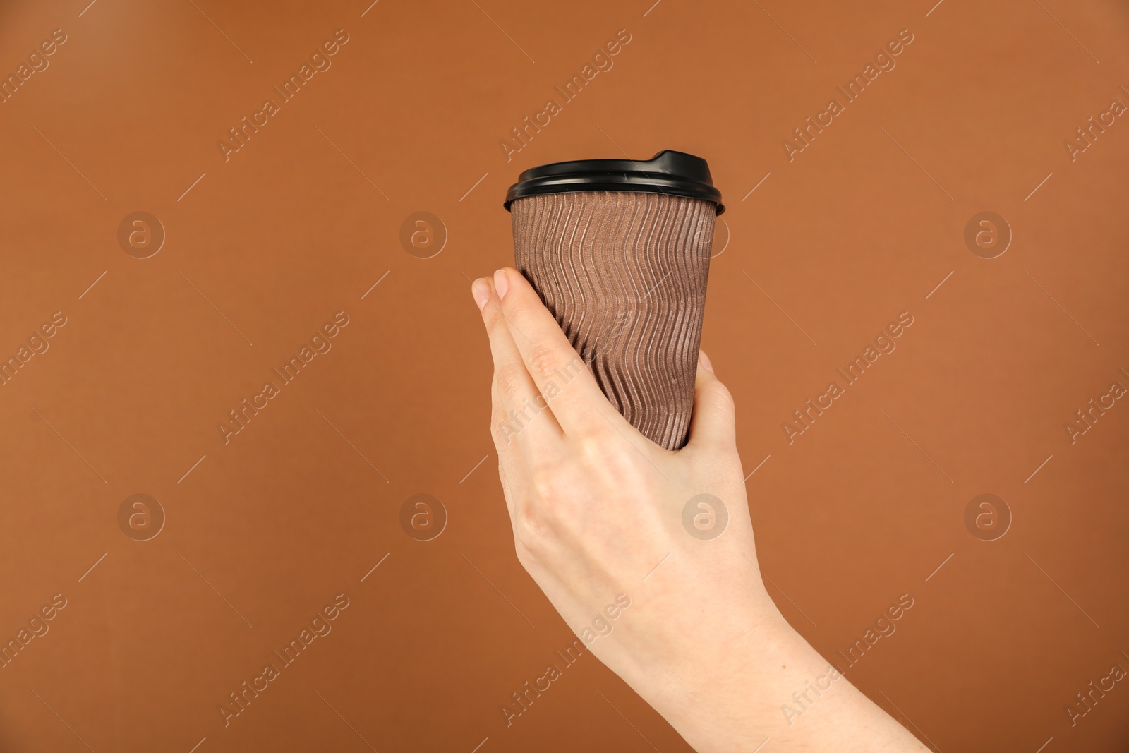 Woman holding paper cup on brown background, closeup. Mockup for design Photo of Woman holding paper cup on brown background, closeup. Mockup for design