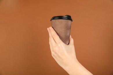 Photo of Woman holding paper cup on brown background, closeup. Mockup for design