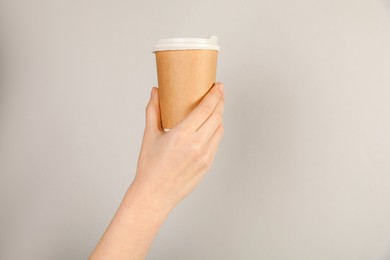 Photo of Woman holding paper cup on grey background, closeup. Mockup for design