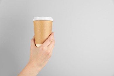 Photo of Woman holding paper cup on grey background, closeup. Mockup for design