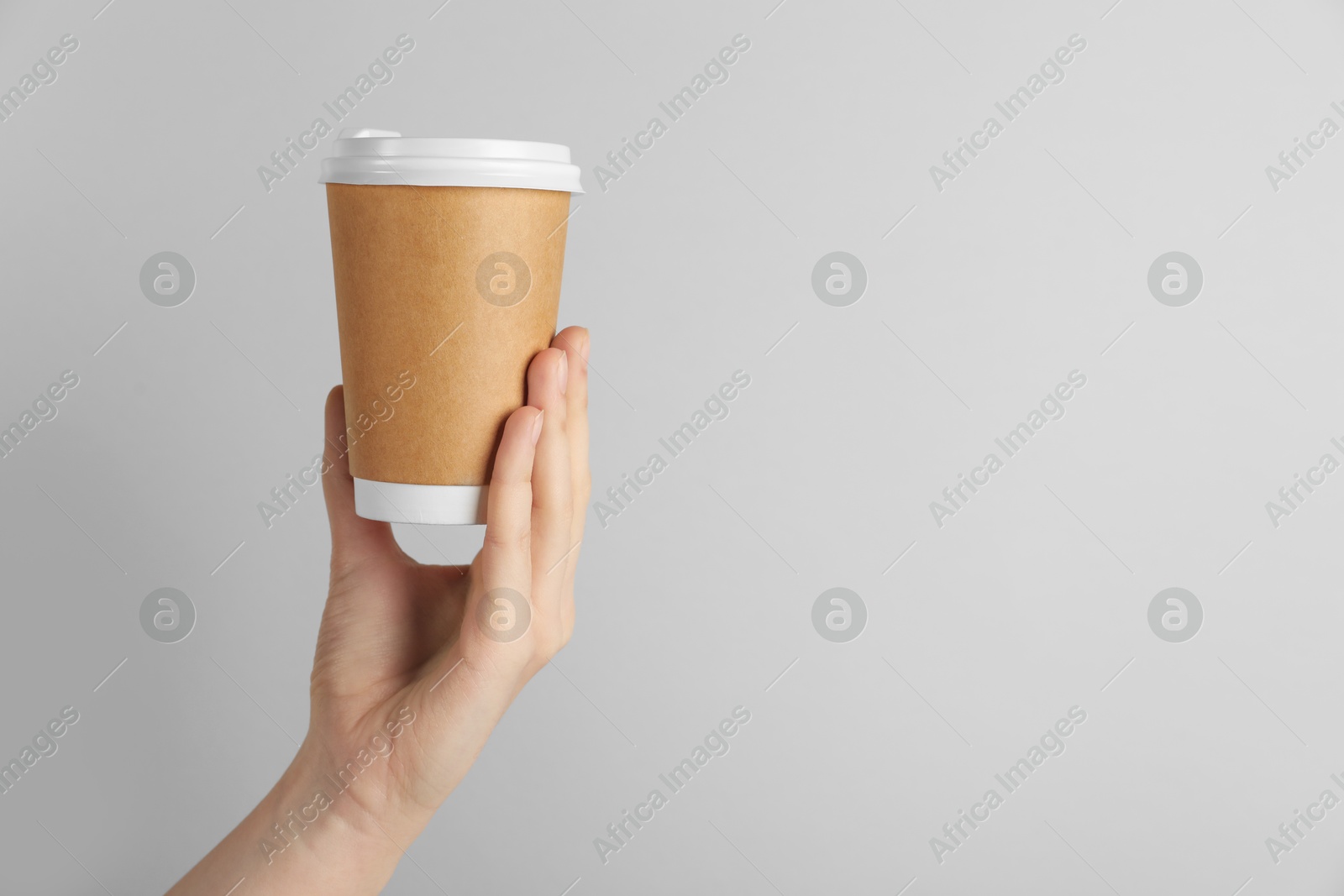 Woman holding paper cup on grey background, closeup. Mockup for design Photo of Woman holding paper cup on grey background, closeup. Mockup for design