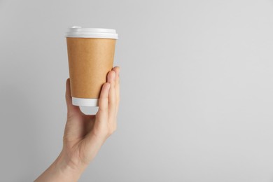 Photo of Woman holding paper cup on grey background, closeup. Mockup for design