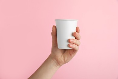 Photo of Woman holding paper cup on pink background, closeup. Mockup for design
