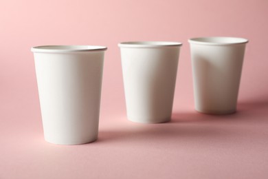 Photo of Paper cups on pink background, closeup. Mockup for design