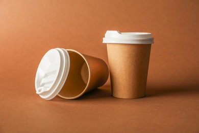 Photo of Paper cups with lids on brown background. Mockup for design