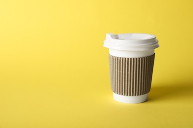 Photo of One paper cup on yellow background. Mockup for design