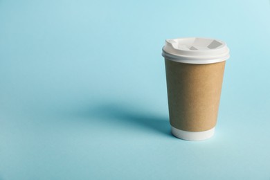 Photo of One paper cup on light blue background. Mockup for design