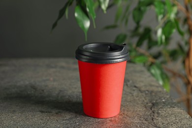 Photo of Paper cup on grey textured table indoors, closeup. Mockup for design