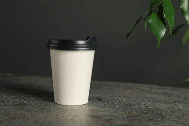 Photo of Paper cup on grey textured table indoors, closeup. Mockup for design