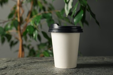 Photo of Paper cup on grey textured table indoors, closeup. Mockup for design