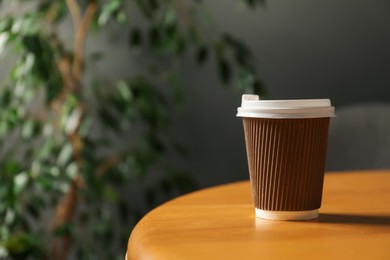 Photo of Paper cup on wooden table indoors, closeup. Mockup for design