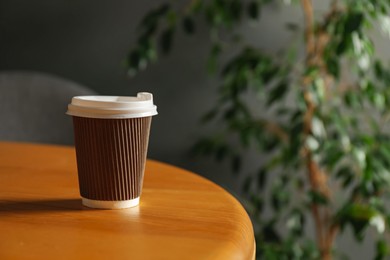 Photo of Paper cup on wooden table indoors, closeup. Mockup for design