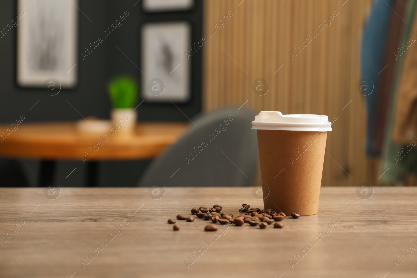 Paper cup and coffee beans on wooden table indoors. Mockup for design Photo of Paper cup and coffee beans on wooden table indoors. Mockup for design