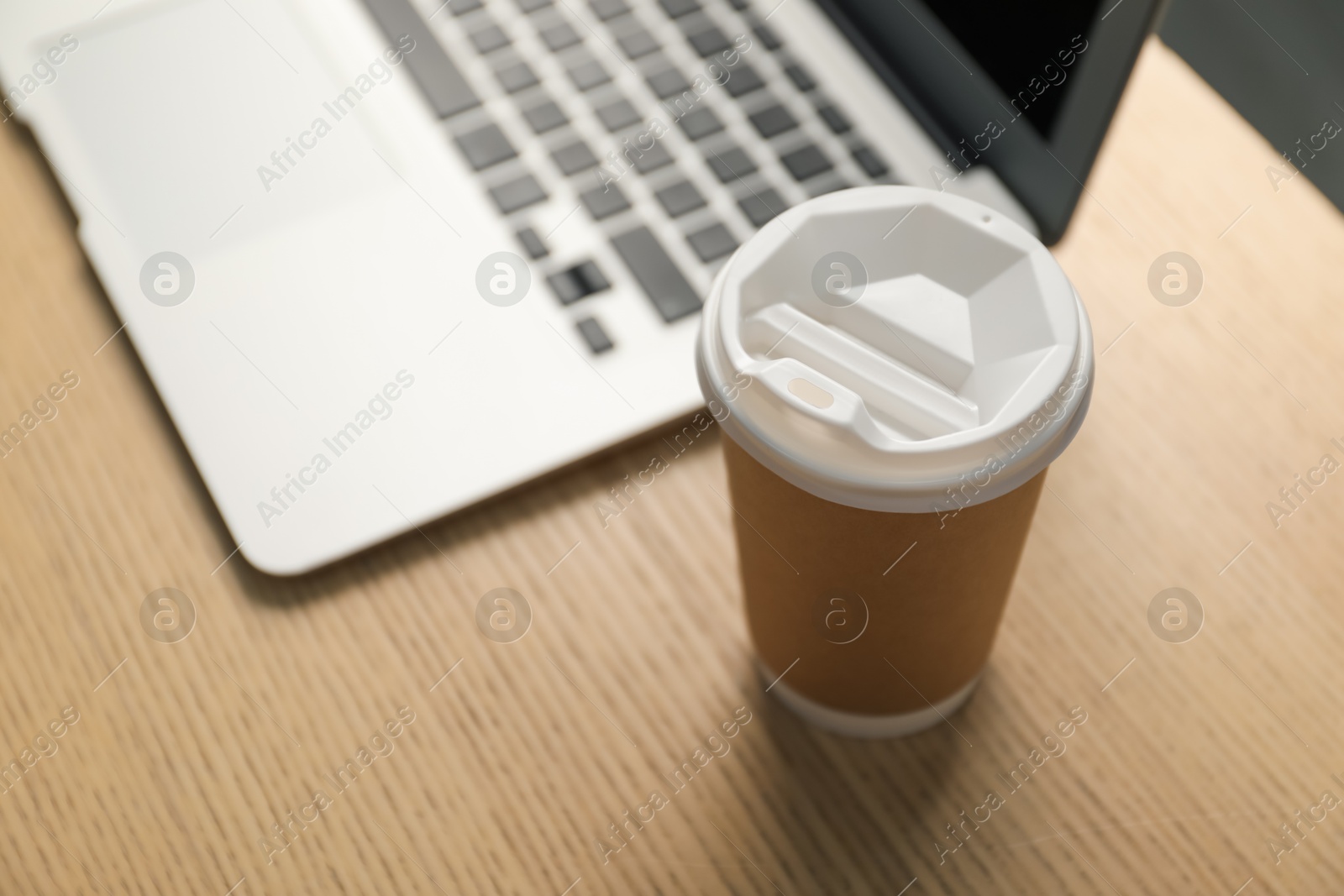 Paper cup and laptop on wooden table, closeup. Mockup for design Photo of Paper cup and laptop on wooden table, closeup. Mockup for design