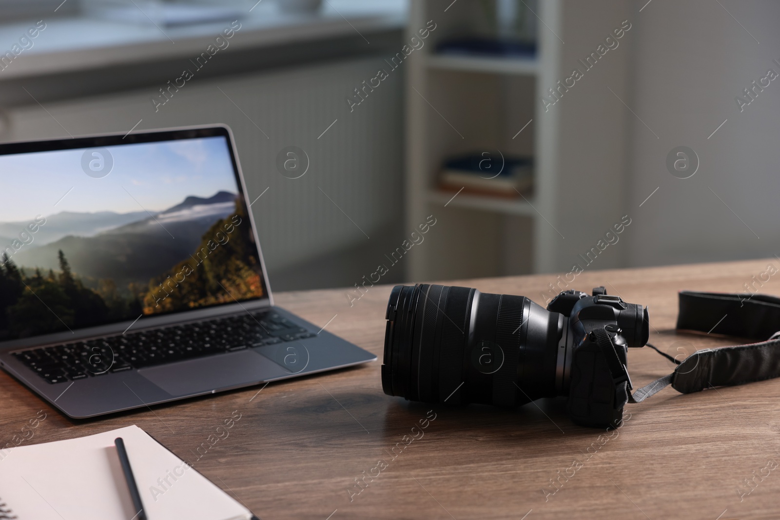 Photo of Professional photo camera, laptop and notepad on wooden desk indoors. Space for text