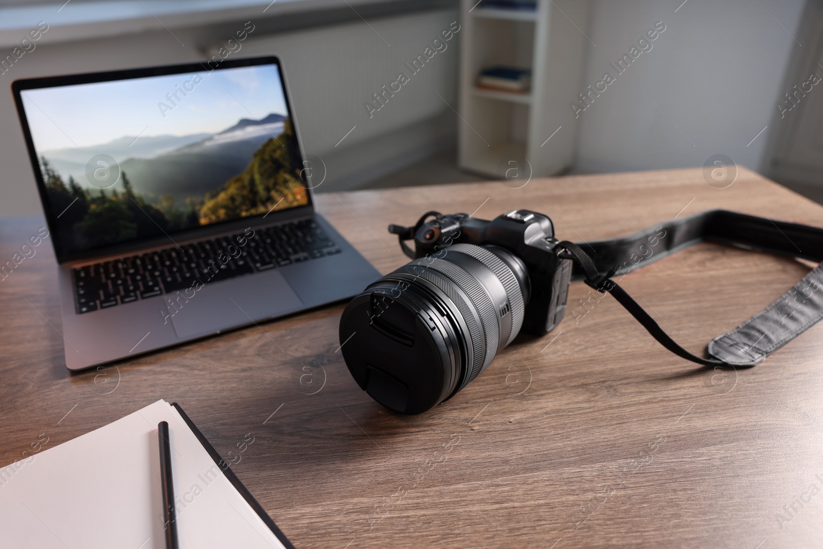 Photo of Professional photo camera, laptop and notepad on wooden desk indoors