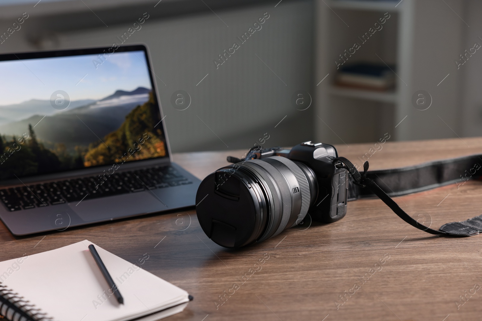 Photo of Professional photo camera, laptop and notepad on wooden desk indoors