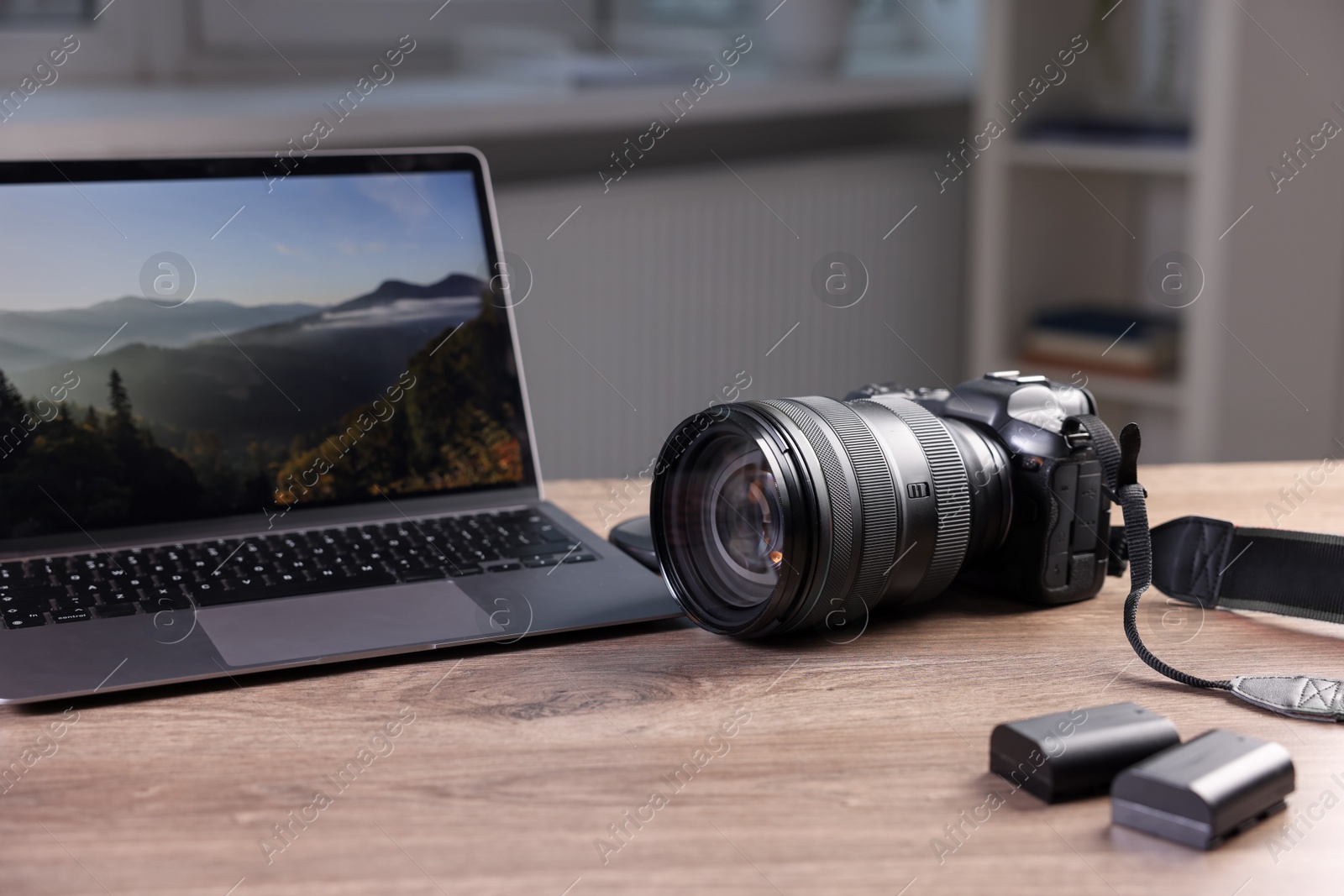 Photo of Professional photo camera and laptop on wooden desk indoors