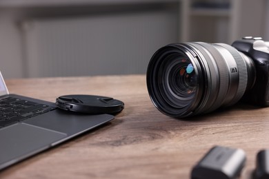 Photo of Professional photo camera and laptop on wooden desk indoors