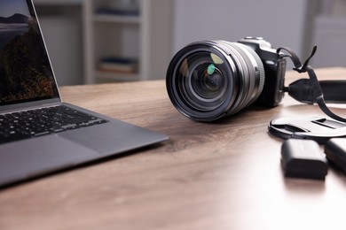 Photo of Professional photo camera and laptop on wooden desk indoors