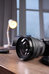 Photo of Professional photo camera on wooden desk indoors, closeup. Space for text