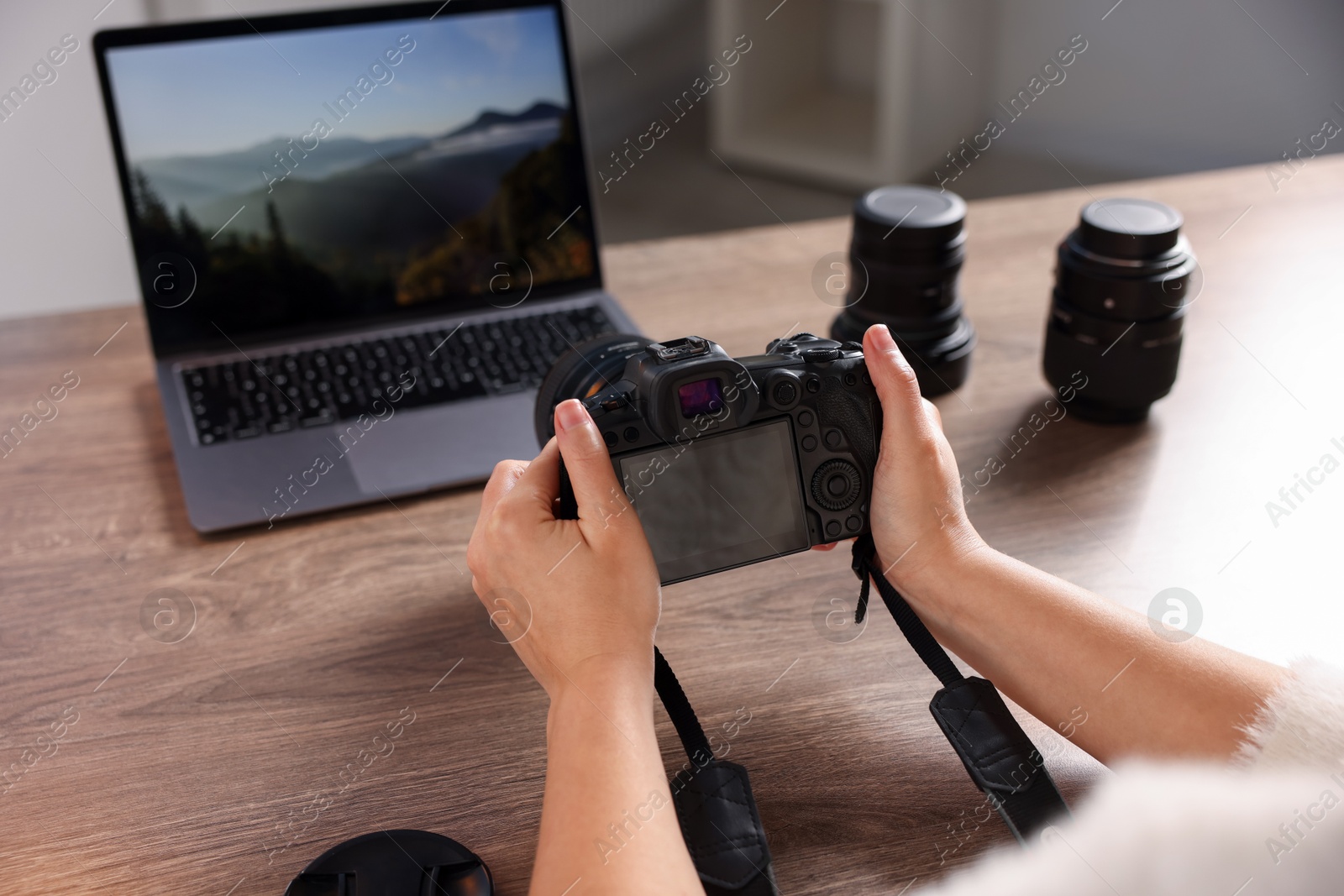 Photo of Photographer with professional camera at wooden desk, closeup