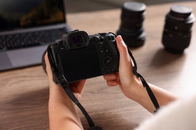 Photo of Photographer with professional camera at wooden desk, closeup