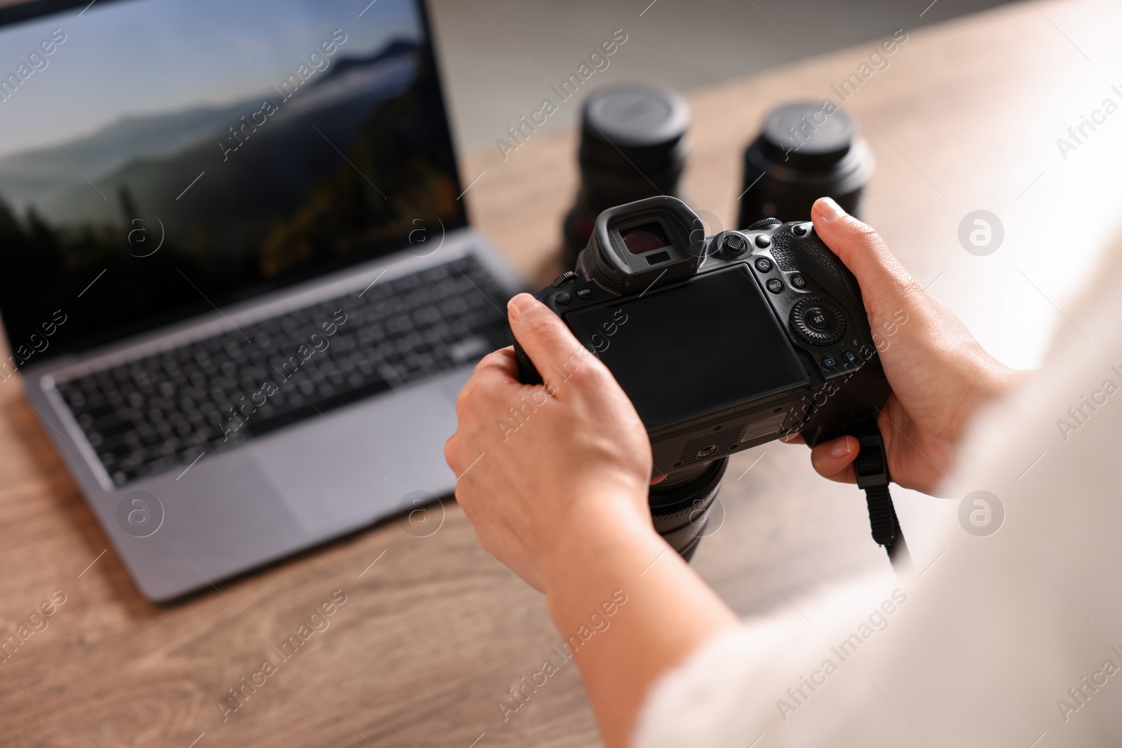 Photo of Photographer with professional camera at wooden desk, closeup