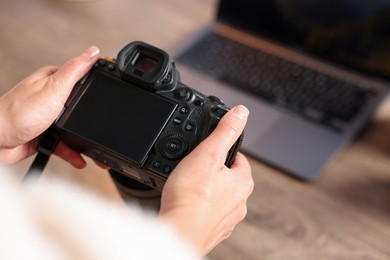 Photo of Photographer with professional camera at wooden desk, closeup