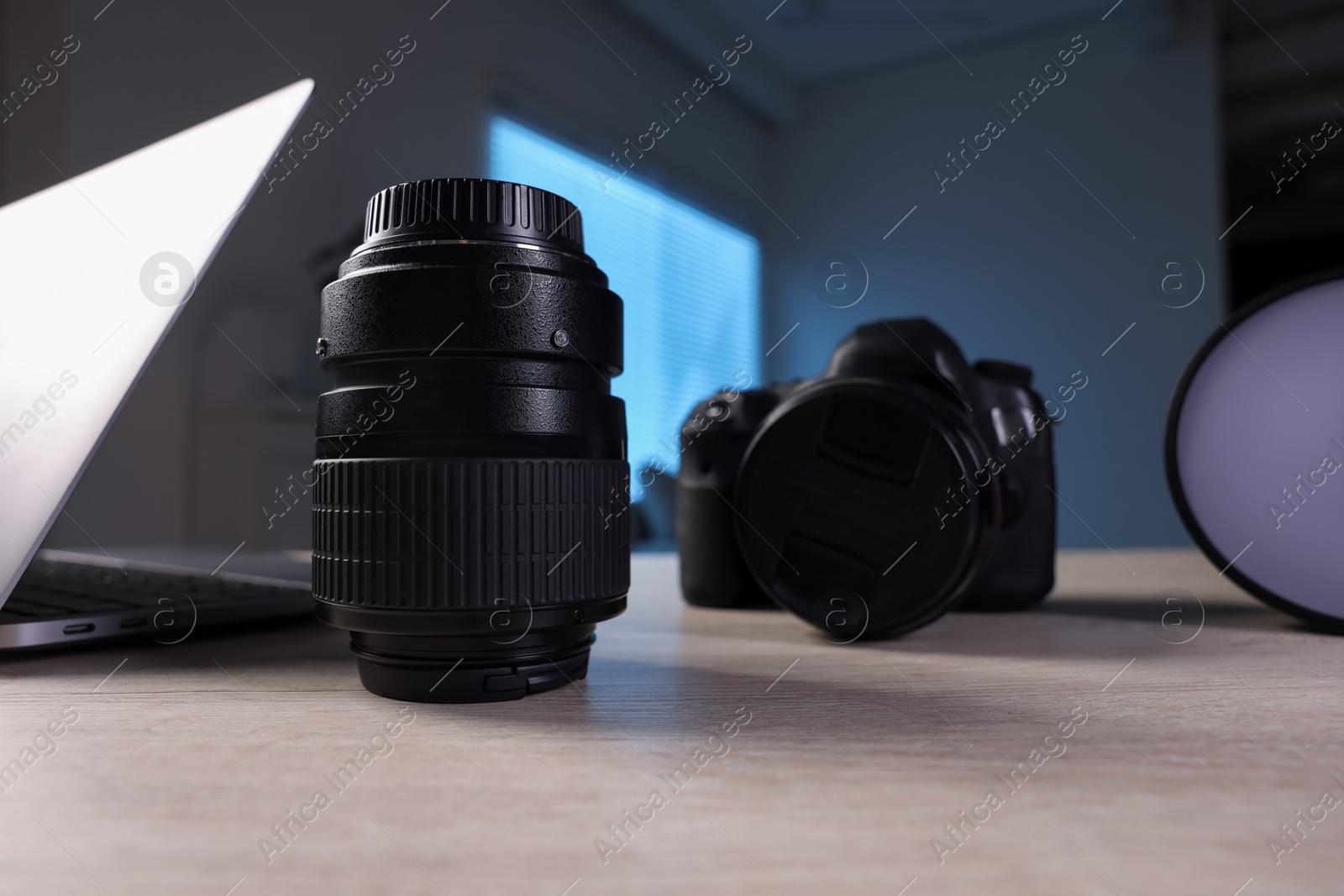 Photo of Professional photo camera, lens, flash and laptop on wooden desk indoors, closeup