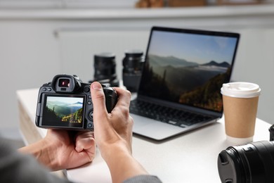 Photo of Photographer with professional camera at white desk indoors, closeup