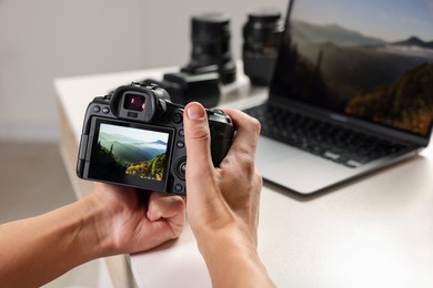 Photo of Photographer with professional camera at white desk indoors, closeup