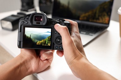 Photo of Photographer with professional camera at white desk indoors, closeup