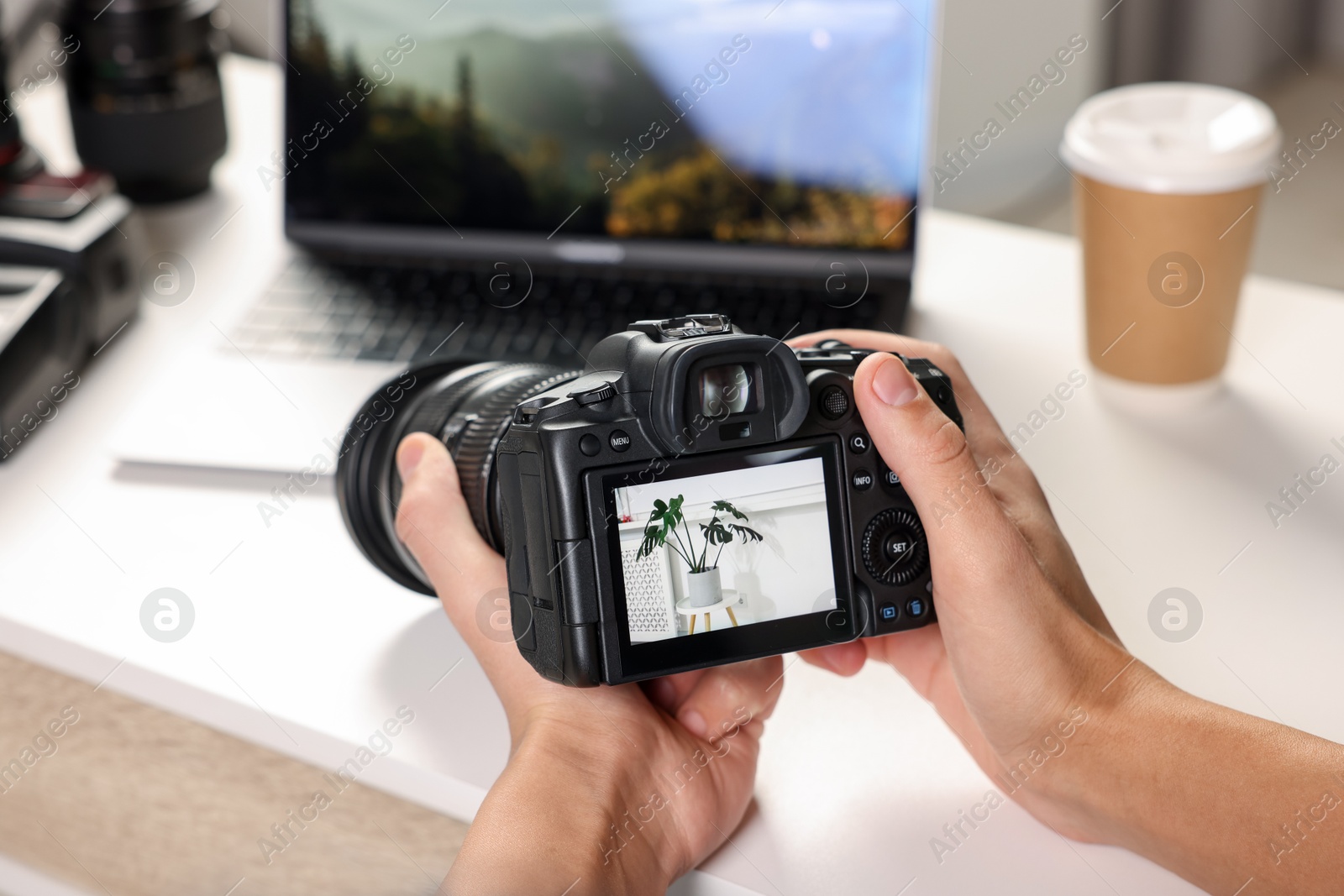 Photo of Photographer with professional camera at white desk indoors, closeup