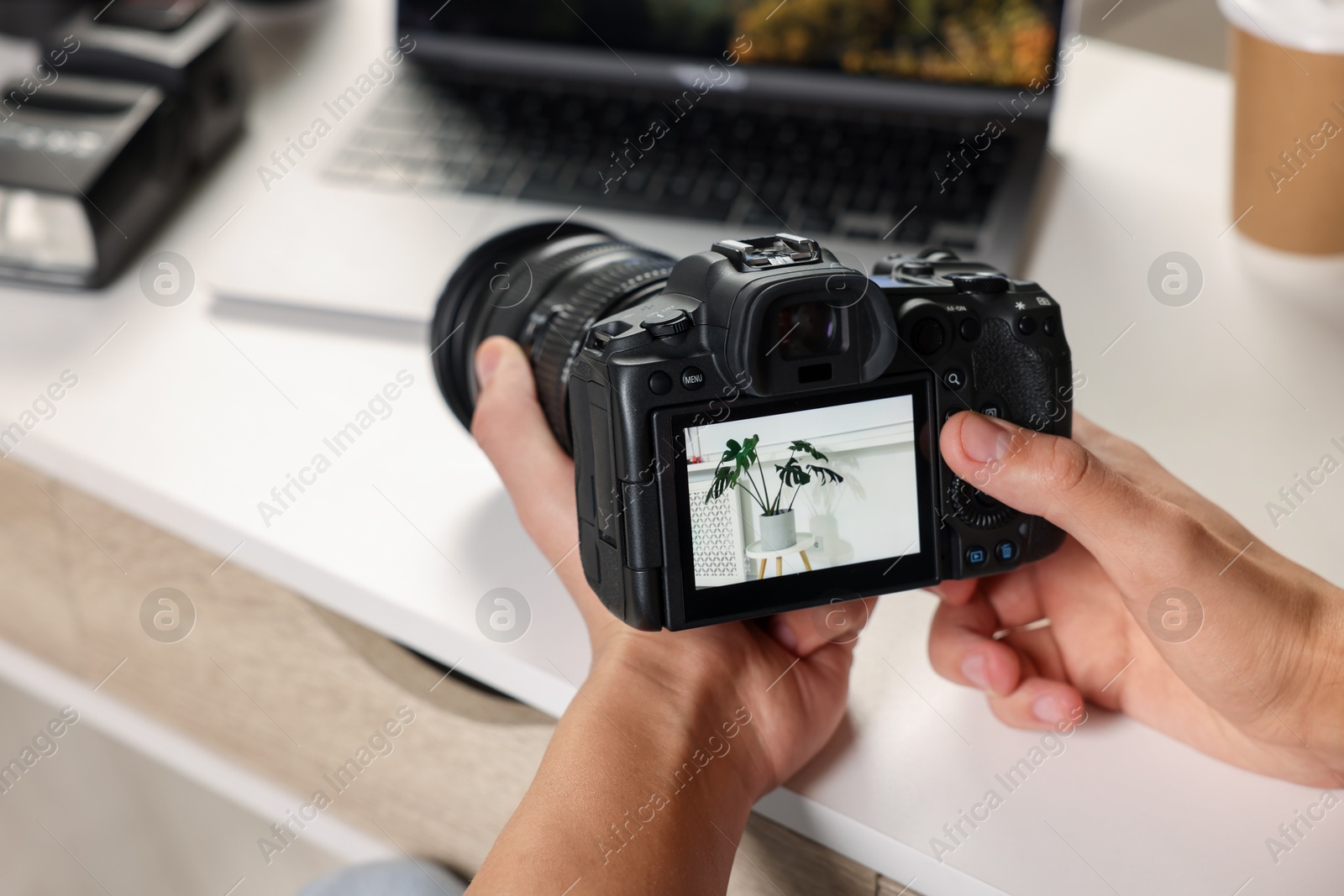 Photo of Photographer with professional camera at white desk indoors, closeup